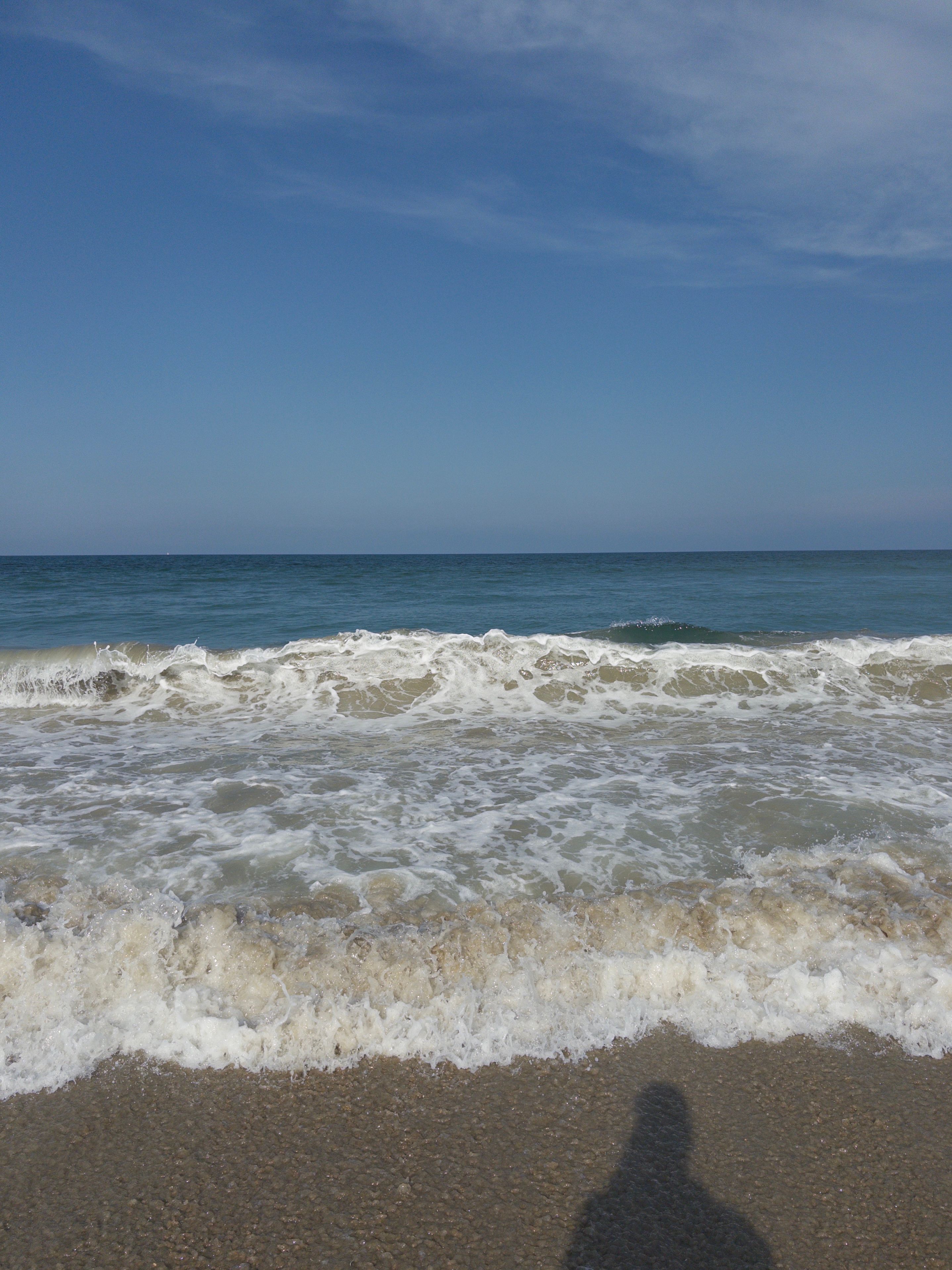Overhead breaking wave, photographer’s shadow on wet sand