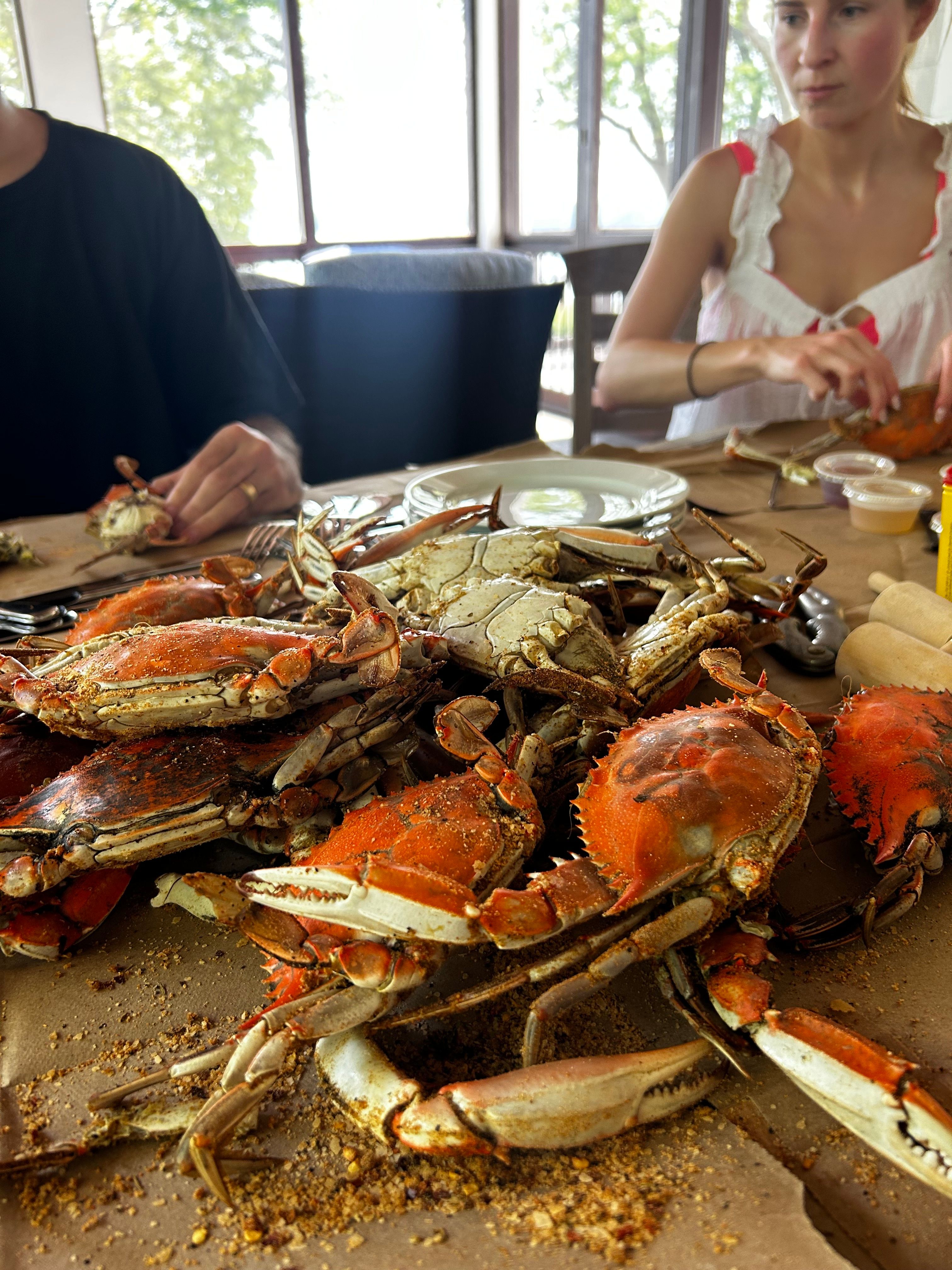 Steamed crabs on brown paper, people picking