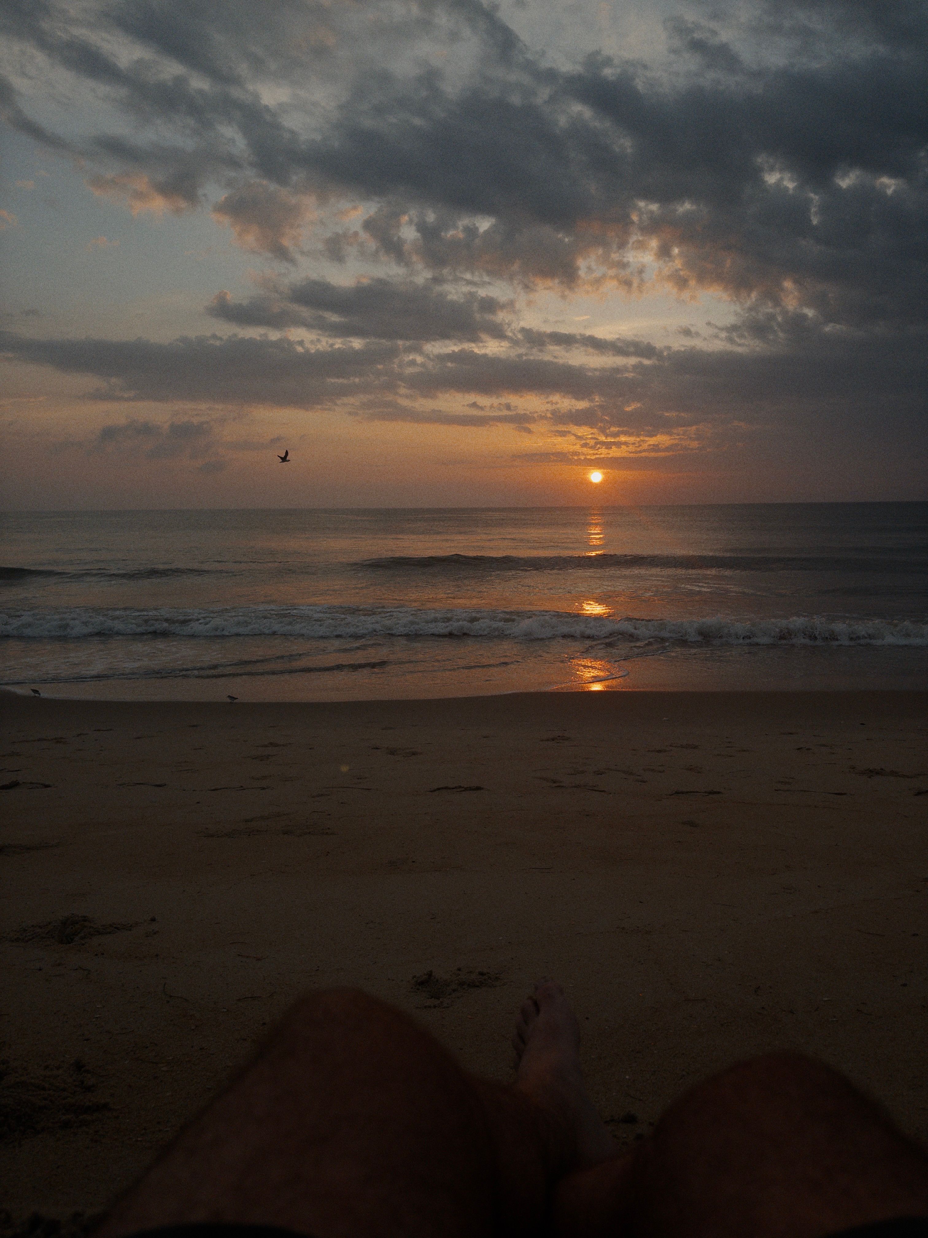 Sitting on the sand looking at sunset over the ocean