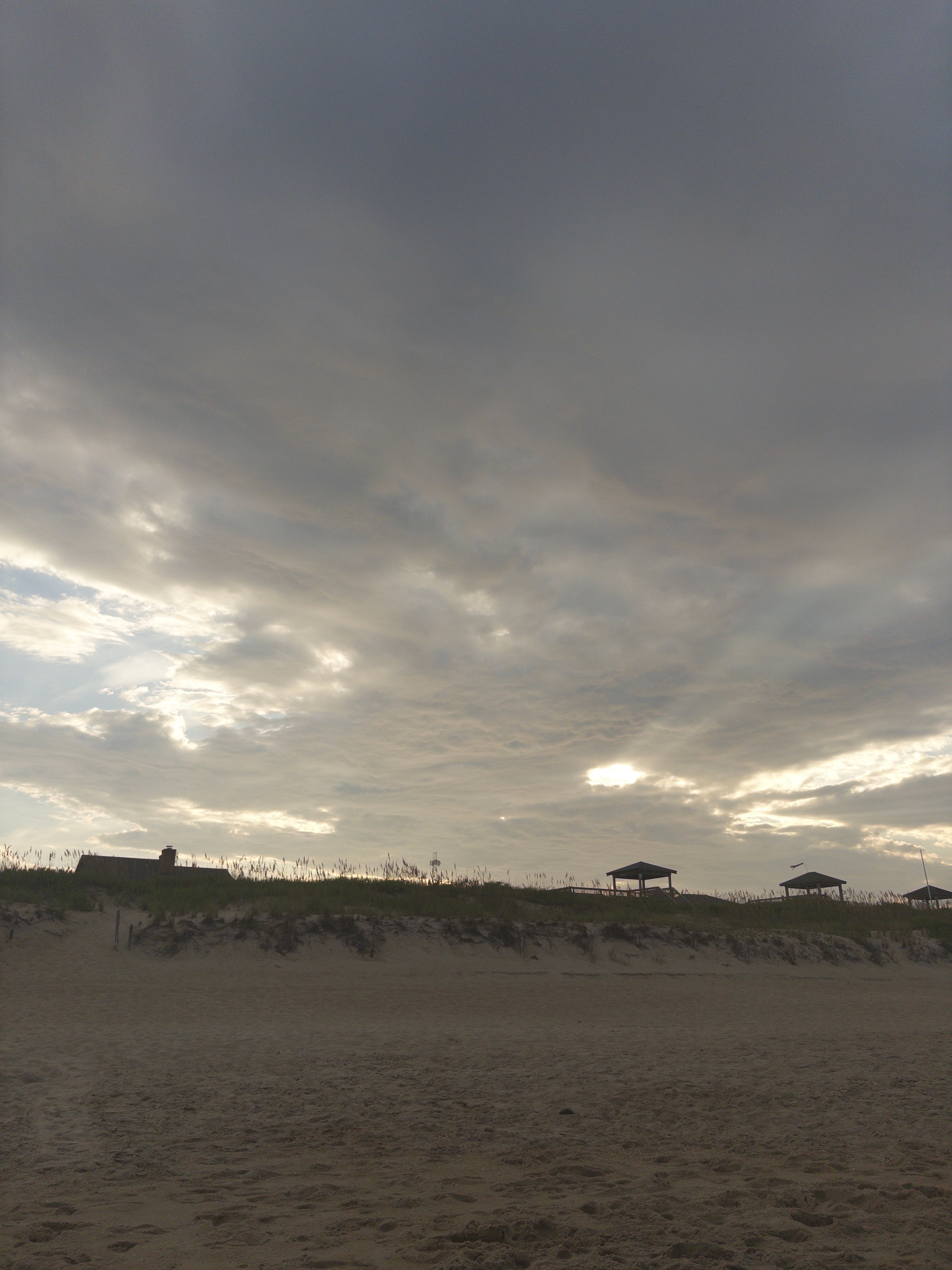 Dune-ridge pavilions silhouetted against a backlit sky